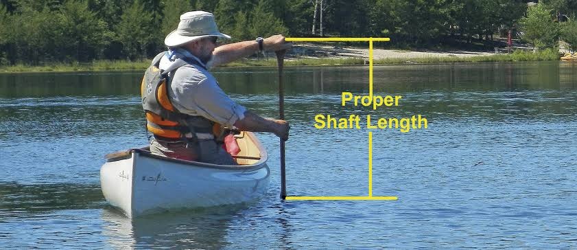 Measuring a canoe paddle against the torso to demonstrate correct canoe paddle sizing