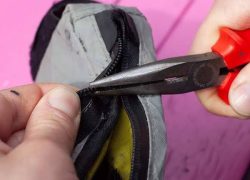 Using pliers to repair a worn zipper slider on a jacket while camping