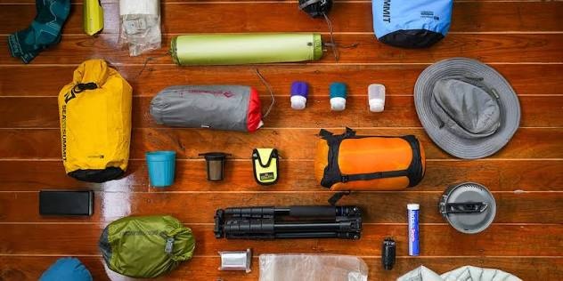 Beginner camping gear laid out in five groups shelter, sleep, kitchen, light and safety
