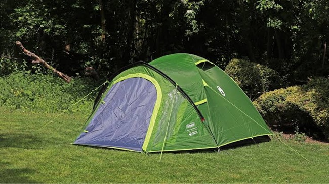Three-person dome tent pitched with rain fly and tensioned guylines on level ground