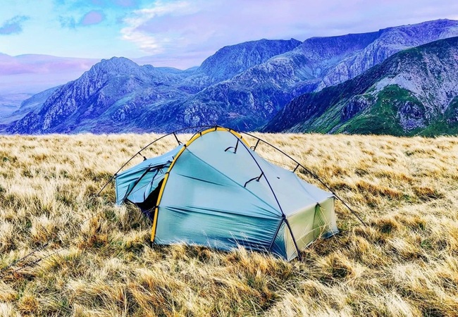 Tent pitched on high ground with rainfly taut during a downpour